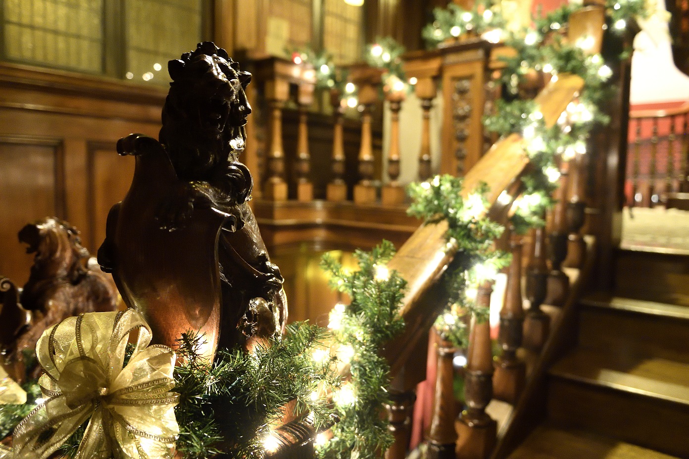 garlands and white lights wrap around the carved bannister in Evergreen's main stairwell