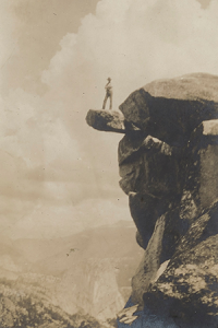 vintage photograph showing figure standing on mountain ledge